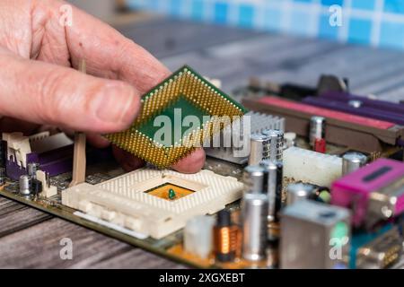 Un tecnico informatico che installa un microprocessore in uno zoccolo della scheda madre. Foto Stock