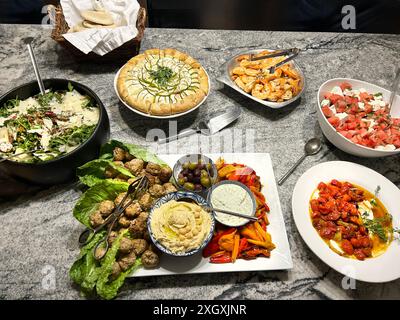 Rucola, insalata di farro ed erbe aromatiche, pomodori arrostiti con yogurt salato, insalata di feta, gamberi grigliati e piatto di mezze Foto Stock
