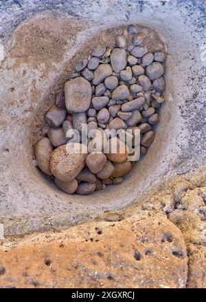 Primo piano di rocce fluviali lucide lavate, ciottoli in un buco nel letto del fiume, cascate Leichhardt, Golfo di Carpentaria, Queensland, Australia Foto Stock