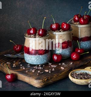 Budini di chia nella foresta nera con ciliegie e pennini di cacao, su un tabellone scuro. Foto Stock