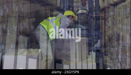 Immagine dell'elaborazione dei dati su un lavoratore maschio caucasico che impilava una scatola su un carrello elevatore in magazzino. Concetto di logistica aziendale e tecnologica Foto Stock