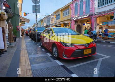 Thailandia. Taxi locale di Phuket di colore giallo e rosso nella città vecchia con sino-portoghese. Strada trafficata. Negozi e ristoranti nella città vecchia. Attrazione turistica Foto Stock