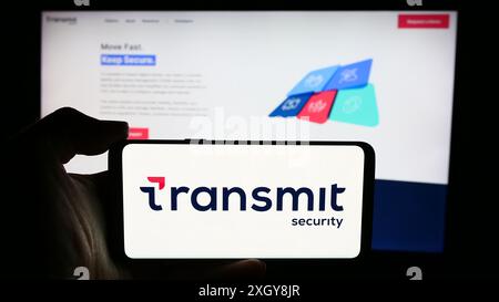 Persona che detiene un cellulare con il logo della società di sicurezza informatica Transmit Security Inc. Di fronte alla pagina Web aziendale. Mettere a fuoco il display del telefono. Foto Stock