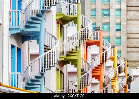 Colorate scale esterne a chiocciola fuori da un edificio dipinto di bianco a Singapore. Singapore è una popolare destinazione turistica dell'Asia. Un paesaggio urbano incredibile Foto Stock