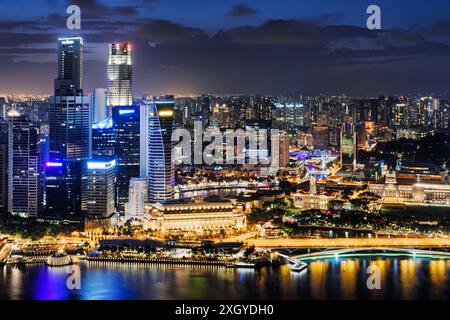 Splendida vista notturna dei grattacieli nel centro di Singapore. Luci colorate della città riflesse nell'acqua di Marina Bay. Un paesaggio urbano incredibile. Foto Stock