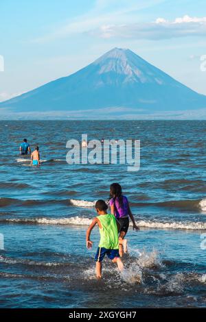 San Jorge, Nicaragua - 25 marzo 2019: Nuotatori gioiosi si crogiolano nelle acque del lago Nicaragua con il vulcano Concepción in vista. Foto Stock