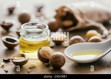 Vista ravvicinata dell'olio naturale di macadamia e delle noci di Macadamia su una tavola di legno Foto Stock