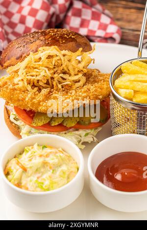 Hamburger di pollo servito con patatine fritte e salse su un piatto di porcellana bianca Foto Stock