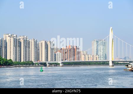 Vista panoramica del Ponte Liede sul fiume delle Perle a Guangzhou, Cina. Gli alti edifici residenziali sono visibili sullo sfondo blu del cielo. Foto Stock