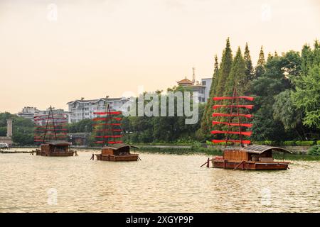 Bellissime navi in legno decorate con bandiere rosse e parcheggiate sul lago di Guilin, Cina. Vista panoramica al tramonto. Foto Stock