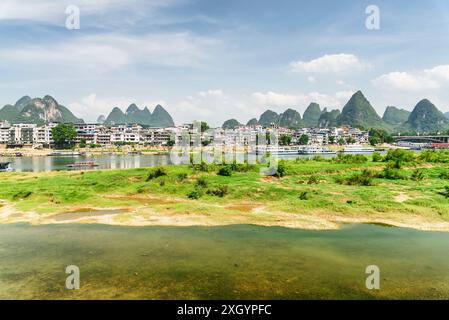 Splendida vista della città di Yangshuo e delle montagne carsiche panoramiche sullo sfondo blu del cielo. Le barche turistiche sono visibili sul fiume li (fiume Lijiang), Guilin. Foto Stock