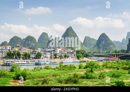 Splendida vista della città di Yangshuo e delle montagne carsiche panoramiche sullo sfondo blu del cielo. Le barche turistiche sono visibili sul fiume li (fiume Lijiang), Guilin. Foto Stock