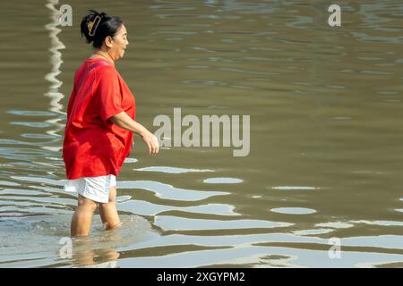 SAMUT PRAKAN, TAILANDIA, febbraio 02 2024, Una donna cammina attraverso una strada allagata Foto Stock