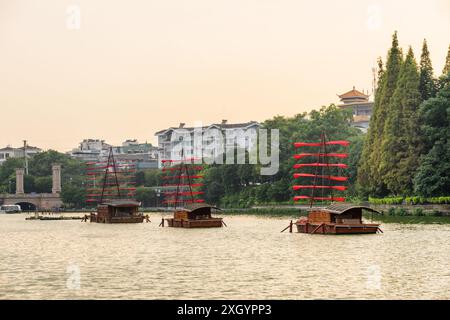 Navi panoramiche in legno decorate con bandiere rosse e parcheggiate sul lago di Guilin, Cina. Splendida vista al tramonto. Foto Stock