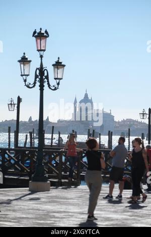 Donna fotografata da un molo sulla Riva degli Schiavoni una lampada veneziana, Chiesa del Santissimo Redentore sulla Giudecca attraverso il bacino Foto Stock