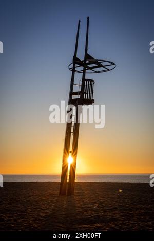 La luce del mattino presto diffonde una calda luce sulla spiaggia di Canet, mettendo in risalto le onde dolci e creando un effetto scintillante sull'acqua. Foto Stock