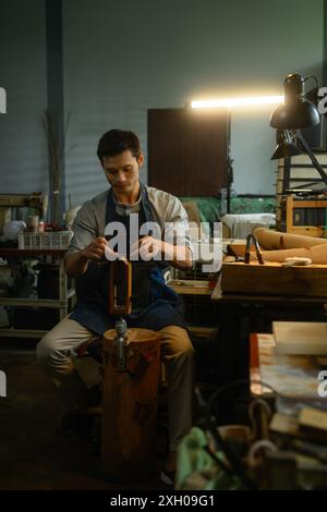 Abile lavoratore di pelli che cucisce, crea prodotti in pelle naturale nell'officina locale Foto Stock