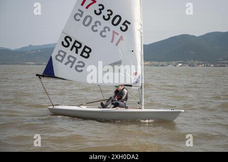 Golubac, Serbia, 9 giugno 2024: Una ragazza adolescente prende parte a una regata a vela di classe laser sul Danubio. Foto Stock