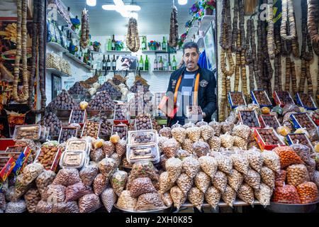 Un venditore di datteri e frutta secca e secca espone una scatola di datteri dall'interno del suo negozio. Si trova nel mercato della medina della città di Fez in Mo Foto Stock