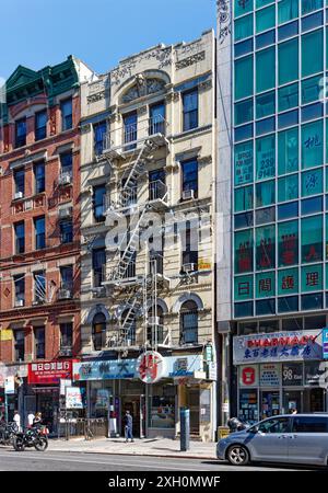 NYC Chinatown: Un tipico edificio di appartamenti in mattoni e terracotta sopra un negozio con cartello cinese, in una tranquilla mattinata nei giorni feriali. Foto Stock