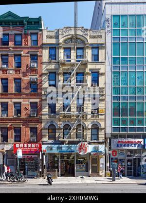 NYC Chinatown: Un tipico edificio di appartamenti in mattoni e terracotta sopra un negozio con cartello cinese, in una tranquilla mattinata nei giorni feriali. Foto Stock