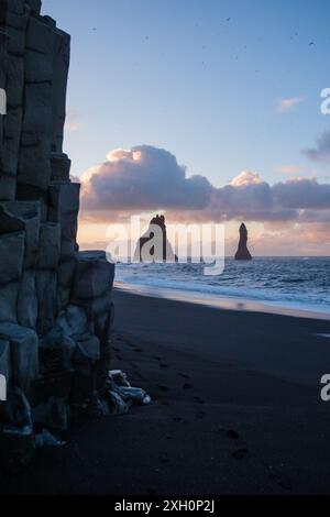 Vista all'alba della spiaggia di Reynisfjara con le sue iconiche faraglioni di mare, situata sulla costa meridionale dell'Islanda. Foto Stock