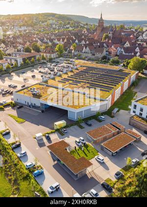 Vista aerea di una città con un grande edificio con pannelli solari installati sul tetto, un parcheggio e case circostanti, Weil der Stadt, Germania Foto Stock