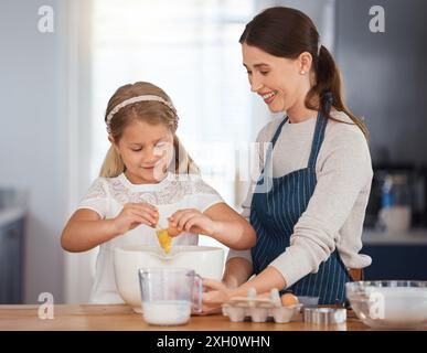 Donna, bambino e cuocere in cucina, famiglia e bambino che assistono per le abilità culinarie o si uniscono. Insegnare, sviluppare le ragazze e rompere l'uovo Foto Stock