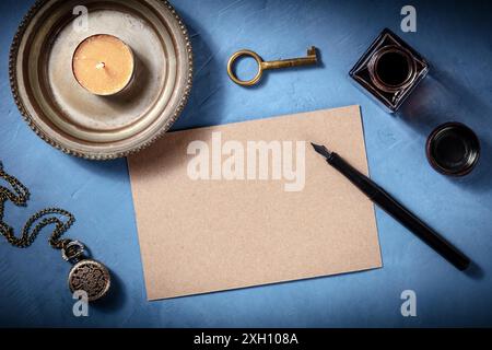 Brown crea un modello di carta per una presentazione di invito o di un biglietto d'auguri, scattata dall'alto con una penna a inchiostro e oggetti vintage su un blu Foto Stock