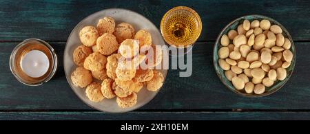 Amaretti, biscotti tradizionali italiani alle mandorle, un panorama con un bicchiere di liquore amaretto, su uno sfondo di legno blu scuro Foto Stock