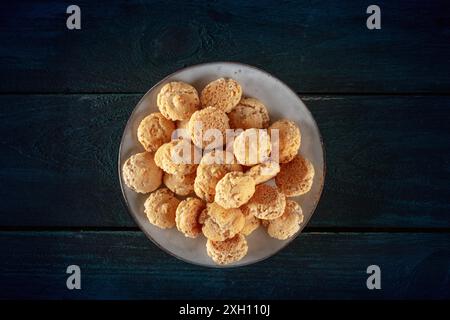 Amaretti, biscotti tradizionali italiani alle mandorle, sparati dall'alto su uno sfondo di legno blu scuro Foto Stock