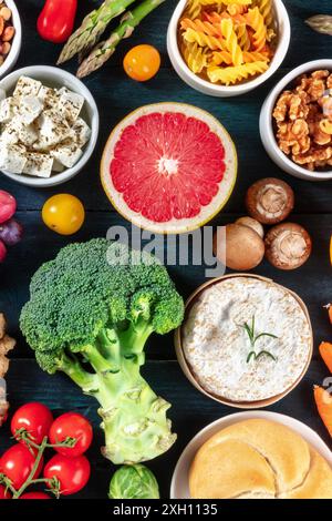 Dieta vegetariana, colpo d'asta. Frutta e verdura, formaggio, funghi, noci, pasta, pane, una varietà di cibi su sfondo di legno blu scuro Foto Stock