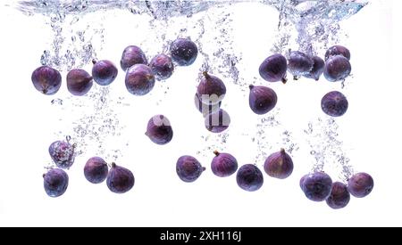 Fichi freschi che cadono nell'acqua isolati su sfondo bianco. Fotografia del cibo. Copia sfondo spazio Foto Stock