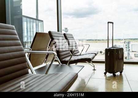 Un'immagine di posti a sedere vuoti per l'aeroporto accanto al bagaglio vicino a una finestra con vista Foto Stock