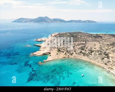 Una splendida vista aerea che mostra le acque turchesi di pori Beach sull'isola greca di Koufonisia, con una barca solitaria ancorata nella tranquilla baia. Foto Stock