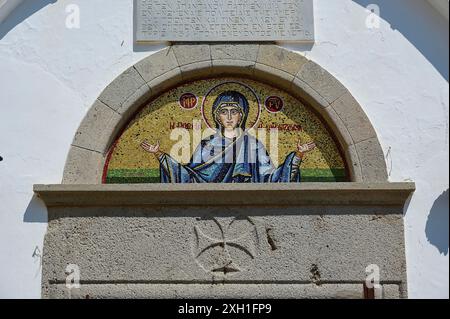 Chiesa a cupola di Diasososuan, primo piano di un mosaico che mostra Maria con le braccia allungate, incastonata in un'apertura semicircolare su un edificio bianco Foto Stock