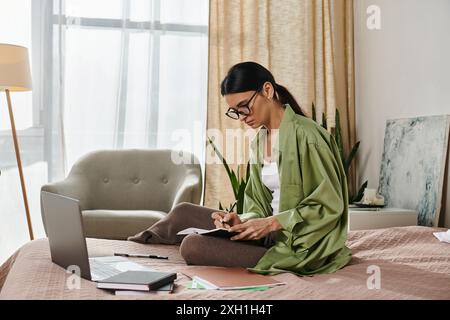 Donna con un abbigliamento casual che lavora su un laptop su un letto. Foto Stock