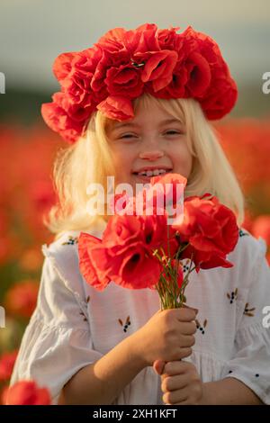 Una giovane ragazza che indossa un copricapo di fiori rossi regge un mazzo di fiori rossi Foto Stock