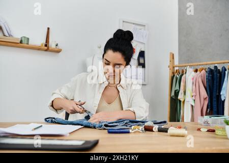 Una giovane donna indossa i vestiti, cucendo e creando su un pezzo di stoffa. Foto Stock