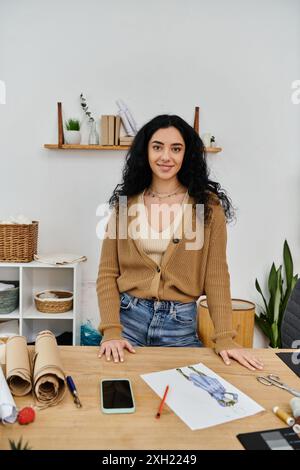 Una giovane donna in un abbigliamento casual che lavora a una scrivania e indossa i suoi abiti per una moda sostenibile. Foto Stock