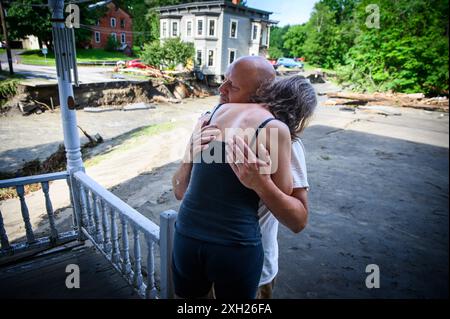 Plainfield, Vermont, Stati Uniti. 11 luglio 2024. Jim e Jenni Belotserkovsky si abbracciano dopo che la loro casa è stata inondata quando le piogge torrenziali dai resti dell'uragano Beryl hanno colpito il Vermont centrale, USA, il 10 luglio. Great Brook, un affluente del fiume Winooski, minò la casa in lontananza, che non è la loro casa ma la loro è vicina sul torrente. John Lazenby/Alamy Live News Foto Stock