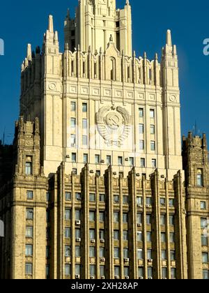 Vista ravvicinata di un grattacielo storico ornato con emblema di rilievo sotto la luce del sole e il cielo azzurro. Foto Stock