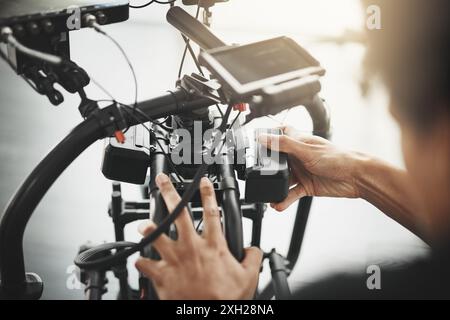 Videografo, fotocamera e mani dell'uomo con obiettivo per la fotografia, la produzione e i media. Dietro le quinte, dietro le quinte e persona con stabilizzatore Foto Stock