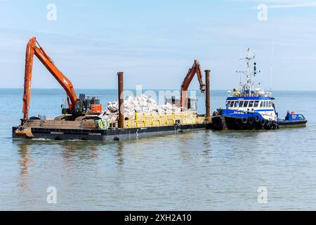 Lavori di protezione contro l’erosione costiera con macchinari provenienti da una chiatta in mare, Cromer, Norfolk, Inghilterra, Regno Unito, Europa Foto Stock