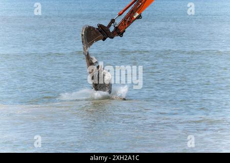 Lavori di protezione contro l’erosione costiera con macchinari provenienti da una chiatta in mare, Cromer, Norfolk, Inghilterra, Regno Unito, Europa Foto Stock