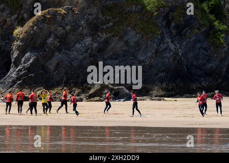 Un gruppo di vacanzieri maschi che giocano a giochi per riscaldarsi prima di una lezione di surf con il Newquay Activity Centre sulla GT Great Western Beach a Newquay in Co Foto Stock