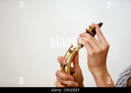 le mani di una ragazza mettono il boccaglio del sassofono Foto Stock