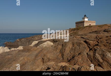 Piccolo faro di S'Arenella, a Girona, in cima ad alcune scogliere ripide tipiche di Capo Creus, hanno un colore rame molto comune in questo capo. Foto Stock