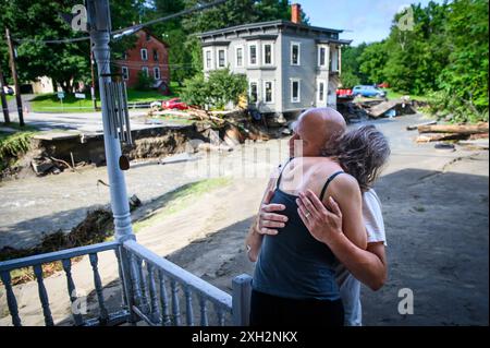 Plainfield, Vermont, Stati Uniti. 11 luglio 2024. Jim e Jenni Belotserkovsky si abbracciano dopo che la loro casa è stata inondata quando le piogge torrenziali dai resti dell'uragano Beryl hanno colpito il Vermont centrale, USA, il 10 luglio. Great Brook, un affluente del fiume Winooski, minò la casa in lontananza, che non è la loro casa ma la loro è vicina sul torrente. John Lazenby/Alamy Live News Foto Stock