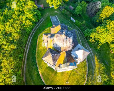 Foto dall'alto della Chiesa di San Giovanni Battista e di nostra Signora del Carmelo circondati da una vegetazione lussureggiante durante il tramonto a Makova hora, Cechia. Foto Stock